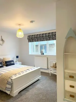 a bedroom with a large bed and a window at Contemporary Holiday apartment in Perranporth