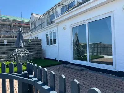 a white house with a patio with an umbrella at Contemporary Holiday apartment in Perranporth