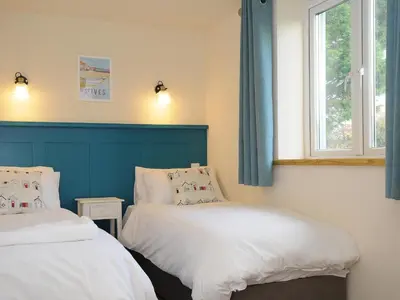 a bedroom with two beds and a window at Gwennel Neyth in Newquay