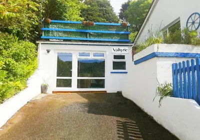 a white house with a door and a balcony at Valkyrie in Perranzabuloe