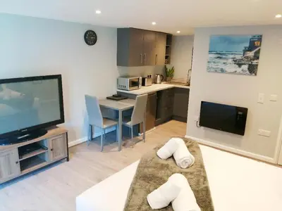 a living room with a television and a kitchen at Valkyrie in Perranzabuloe