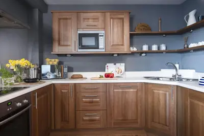 a kitchen with wooden cabinets and a microwave at Bathsheba, Ocean 1 in Newquay