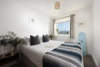 a bedroom with a large white bed and a window at Bathsheba, Ocean 1 in Newquay