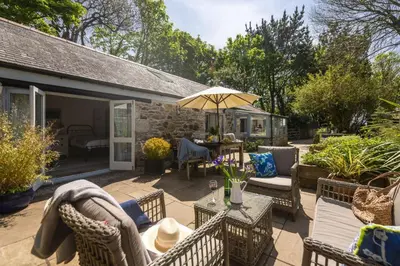 a patio with chairs and a table with an umbrella at Rosehendra in Saint Erth