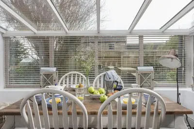 a dining room table with chairs and a window at Rosehendra in Saint Erth