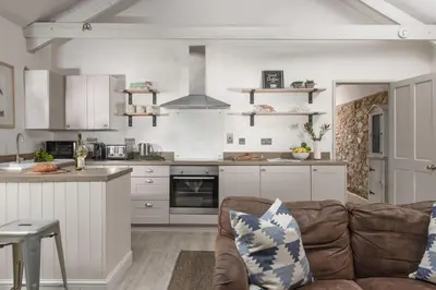 a living room with a couch and a kitchen at Rosehendra in Saint Erth