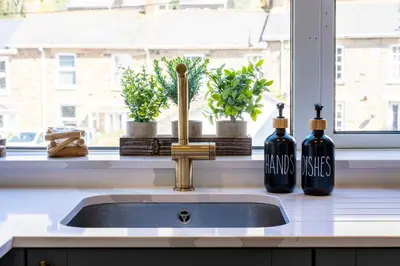 two bottles of wine sitting next to a kitchen sink at Beachspoke Loft in Redruth