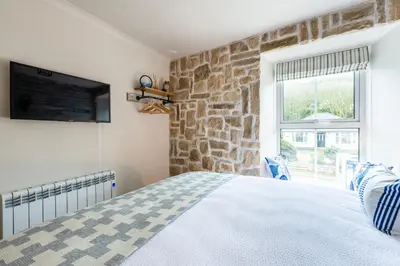 a bedroom with a bed and a stone wall at Beachspoke Loft in Redruth