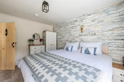 a bedroom with a bed and a wooden wall at Beachspoke Loft in Redruth
