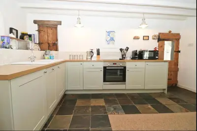 a kitchen with white cabinets and a tile floor at The Roundhouse Tregonce, Padstow, near the sea in St. Issey