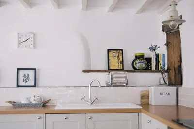 a kitchen with white cabinets and a sink at The Roundhouse Tregonce, Padstow, near the sea in St. Issey