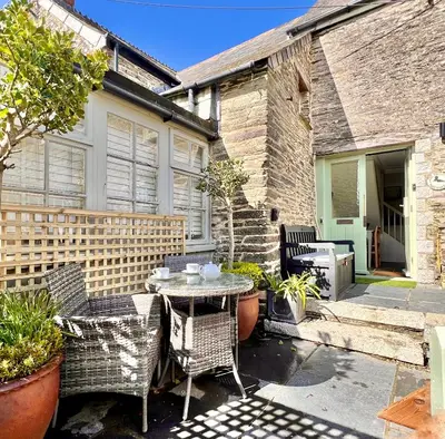 a patio with a table and chairs in front of a house at The Roundhouse Tregonce, Padstow, near the sea in St. Issey