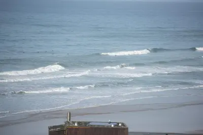 a beach with waves and a building and the ocean at The Penthouse Forty Eight, Ocean 1 in Newquay