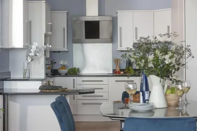 a kitchen with white cabinets and a table with chairs at The Penthouse Forty Eight, Ocean 1 in Newquay