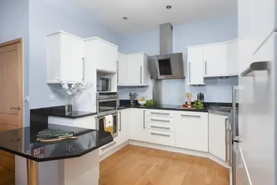 a kitchen with white cabinets and a black counter top at The Penthouse Forty Eight, Ocean 1 in Newquay