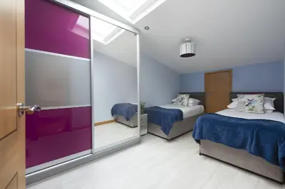 a bedroom with two beds and a sliding glass door at The Penthouse Forty Eight, Ocean 1 in Newquay