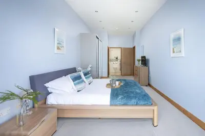 a bedroom with a large bed with a blue blanket at The Penthouse Forty Eight, Ocean 1 in Newquay