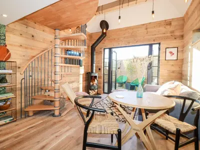 a room with a spiral staircase and a table and chairs at Little Beach Cabin in Newquay