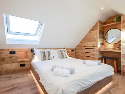 a bedroom with a large white bed with a window at Little Beach Cabin in Newquay