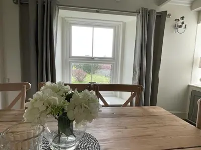 a dining room table with a vase of flowers on it at Beautiful family home, sea views, large garden in Port Isaac