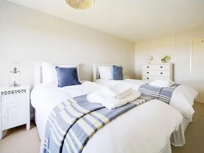 two beds in a bedroom with white and blue at Beautiful family home, sea views, large garden in Port Isaac