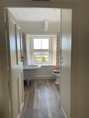 a bathroom with a tub and a toilet and a window at Beautiful family home, sea views, large garden in Port Isaac