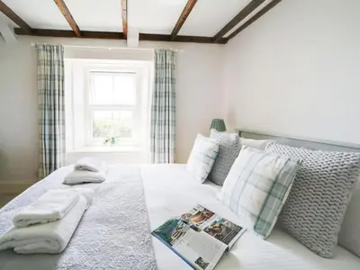 a bedroom with a bed with a couch and a window at Beautiful family home, sea views, large garden in Port Isaac