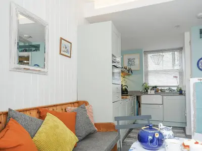 a living room with a couch and a kitchen at Zawn Nook in Falmouth