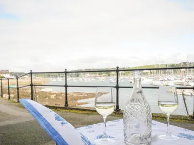 a bottle of wine and two glasses on a table at Zawn Nook in Falmouth