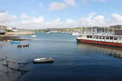 a boat in the water next to a dock with boats at Zawn Nook in Falmouth