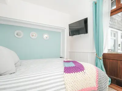 a bedroom with a bed and a tv on a wall at Zawn Nook in Falmouth