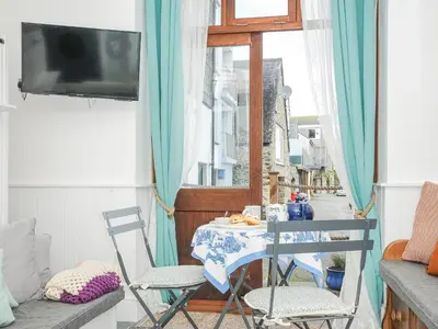 a room with a table and chairs and a tv at Zawn Nook in Falmouth