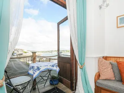a balcony with a chair and a table and a window at Zawn Nook in Falmouth