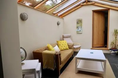 a living room with a couch and a table at Cosy thatched Cottage sleeps 6 near Portscatho! in Porthscatho