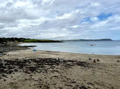 a beach with people on the sand and the water at Cosy thatched Cottage sleeps 6 near Portscatho! in Porthscatho
