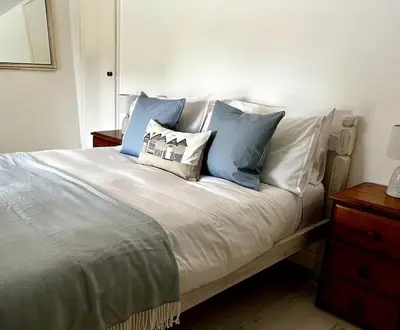 a bedroom with a bed with blue and white pillows at Cosy thatched Cottage sleeps 6 near Portscatho! in Porthscatho