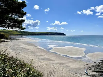 a beach with a tree and the ocean on a sunny day at Cosy thatched Cottage sleeps 6 near Portscatho! in Porthscatho
