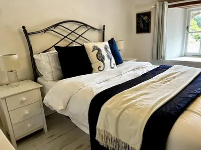 a bedroom with a bed with a black and white comforter at Cosy thatched Cottage sleeps 6 near Portscatho! in Porthscatho