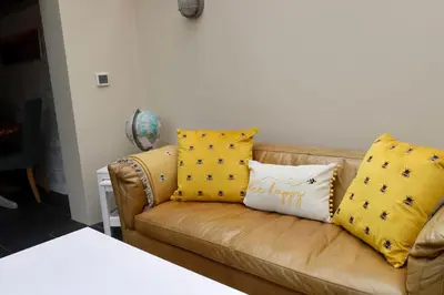 a brown couch with yellow pillows on it at Cosy thatched Cottage sleeps 6 near Portscatho! in Porthscatho