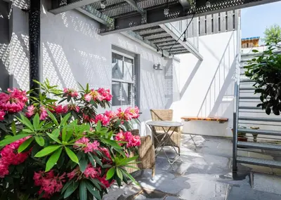a patio with pink flowers and a chair at Georgian Apartment with Courtyard in Boscastle - Ideal for Couples and Families in Boscastle