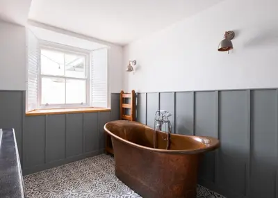 a bath tub in a bathroom with a window at Georgian Apartment with Courtyard in Boscastle - Ideal for Couples and Families in Boscastle