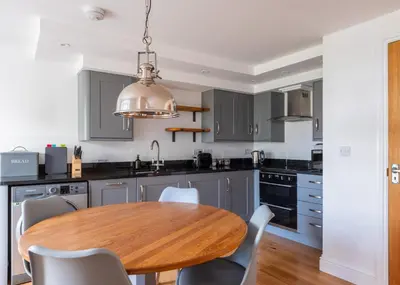 a kitchen with a wooden table and a kitchen with gray cabinets at Georgian Apartment with Courtyard in Boscastle - Ideal for Couples and Families in Boscastle