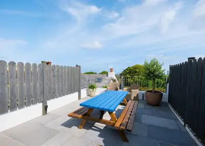 a blue picnic table on a patio with a fence at Georgian Apartment with Courtyard in Boscastle - Ideal for Couples and Families in Boscastle