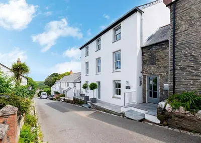 an exterior view of a white house in a village at Georgian Apartment with Courtyard in Boscastle - Ideal for Couples and Families in Boscastle