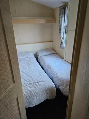two beds in a small room with a window at 113 Caravan at meadow lakes in St Austell