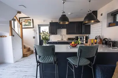 a kitchen with black cabinets and a counter with chairs at THE ANNEXE AT UPPER BEACH HOUSE in Portreath
