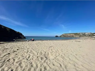 a person sitting on a sandy beach next to the ocean at THE ANNEXE AT UPPER BEACH HOUSE in Portreath