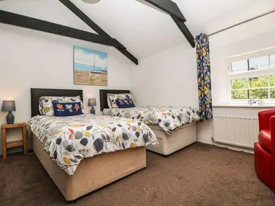a bedroom with two beds and a red chair at The Granary in Bodmin