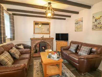 a living room with leather couches and a fireplace at The Granary in Bodmin