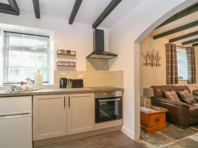 a kitchen with a stove top oven next to a couch at The Granary in Bodmin